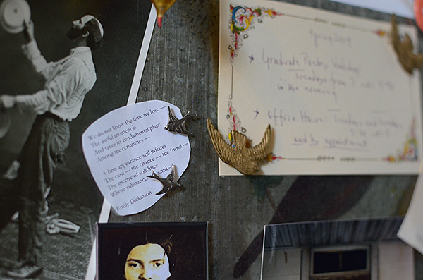 Closeup of door; postcard of man juggling, Dickinson poem pinned by two small metal birds, Dickinson portrait, handwritten office hours pinned by larger gold metal bird in flight; text of Dickinson poem