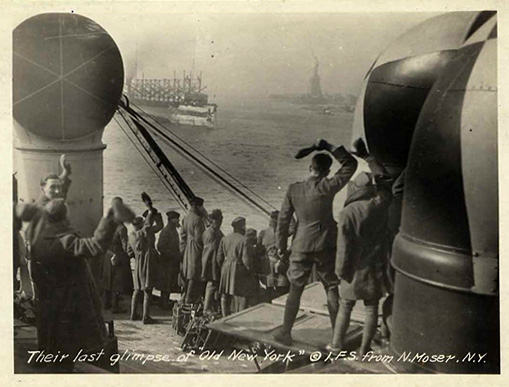 WW1 troops on a transport ship; statue of liberty in distance.