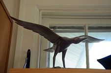 Bird statue with spread wings on a shelf.