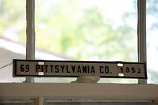 Narrow metal license plate on windows sash reading “69 Pittsylvania Co. 1852.”