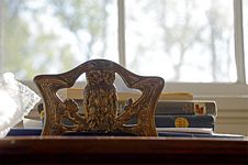 Brass owl bookend in front of stacked books and window.