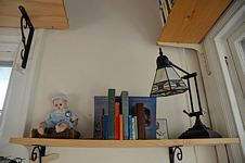 Shelf with baby doll, books, and lamp.