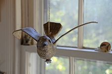Close-up of bird figurine with outstretched wings hanging from a string.