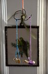Simple mobile suspended from orange yarn to crudely bent wire holding a strand of blue and purple yarn each affixed to fossil or bone fragments.