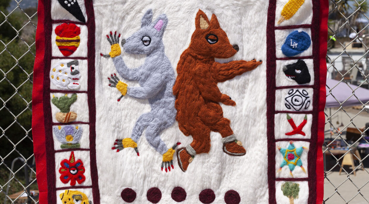 A felted wool sculpture of a coyote and a xoloitzcuintli surrounded by calendar iconography.