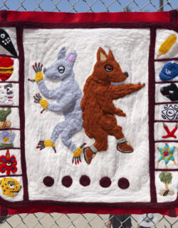 A felted wool sculpture of a coyote and a xoloitzcuintli surrounded by calendar iconography.