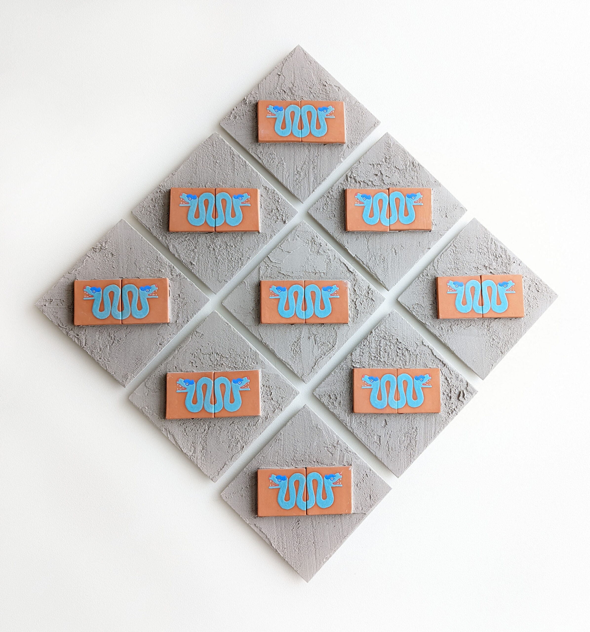 A set of nine ceramic and concrete tiles featuring a repeated image of the coatl.