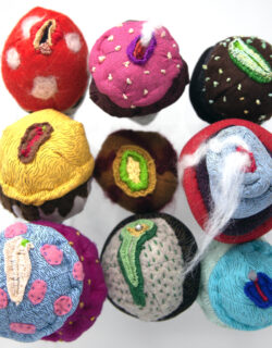 Nine soft-sculpture ice cream cones alluding to vaginas and made of various fabrics, pompoms, beads and accessories. Some of the fabrics are screen printed with patterns.