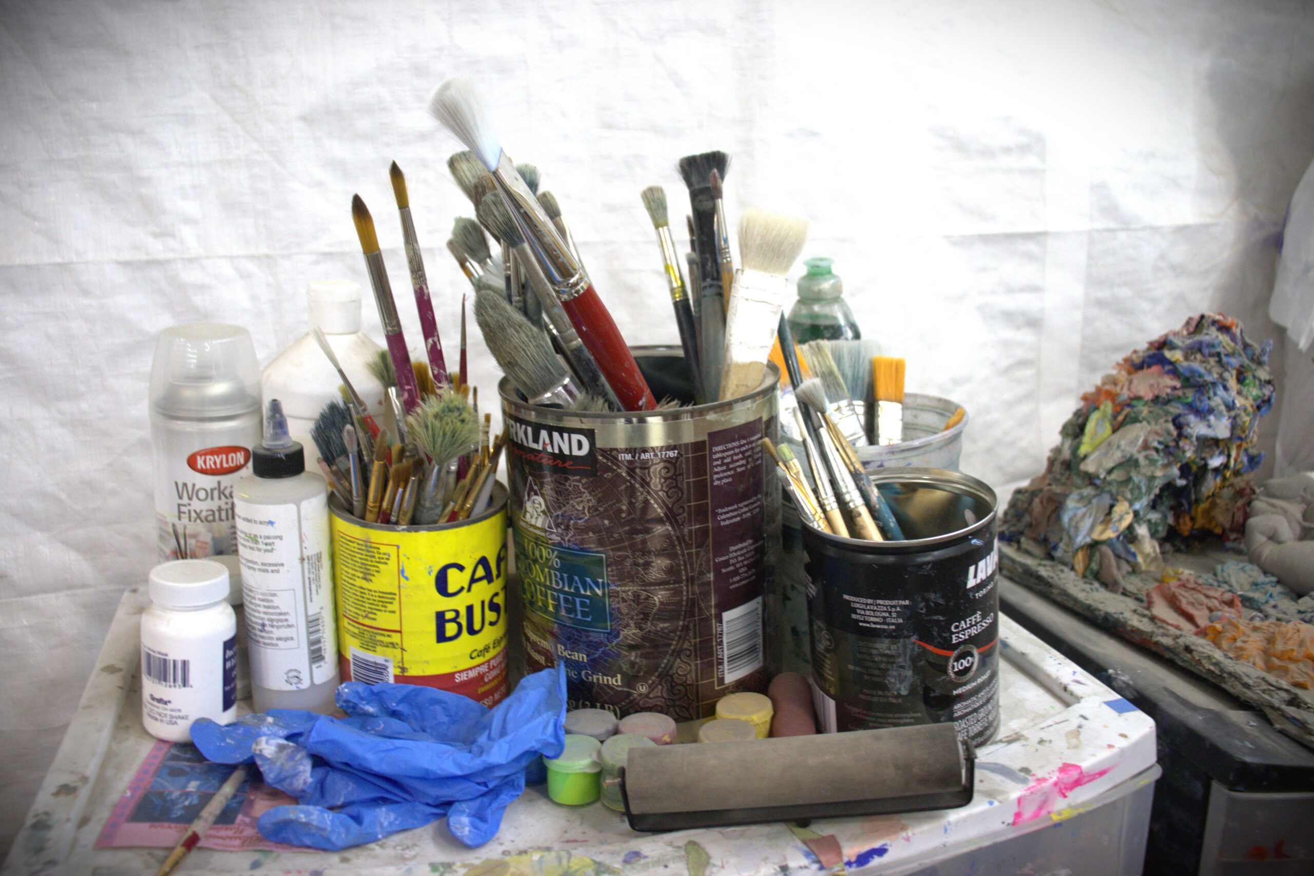 Cans filled with many paint brushes.