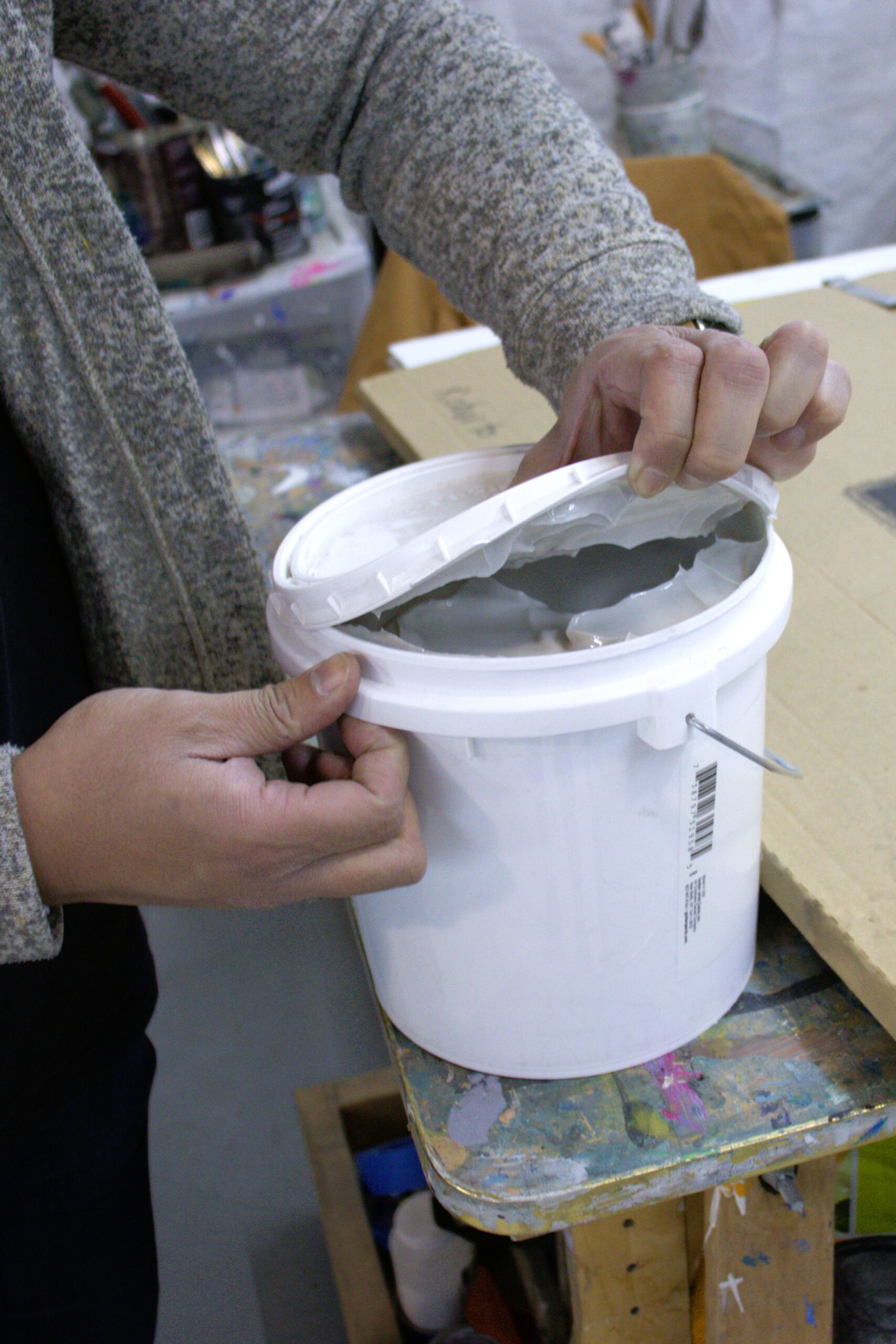 Roberto Jamora opens a tub of pumice medium.