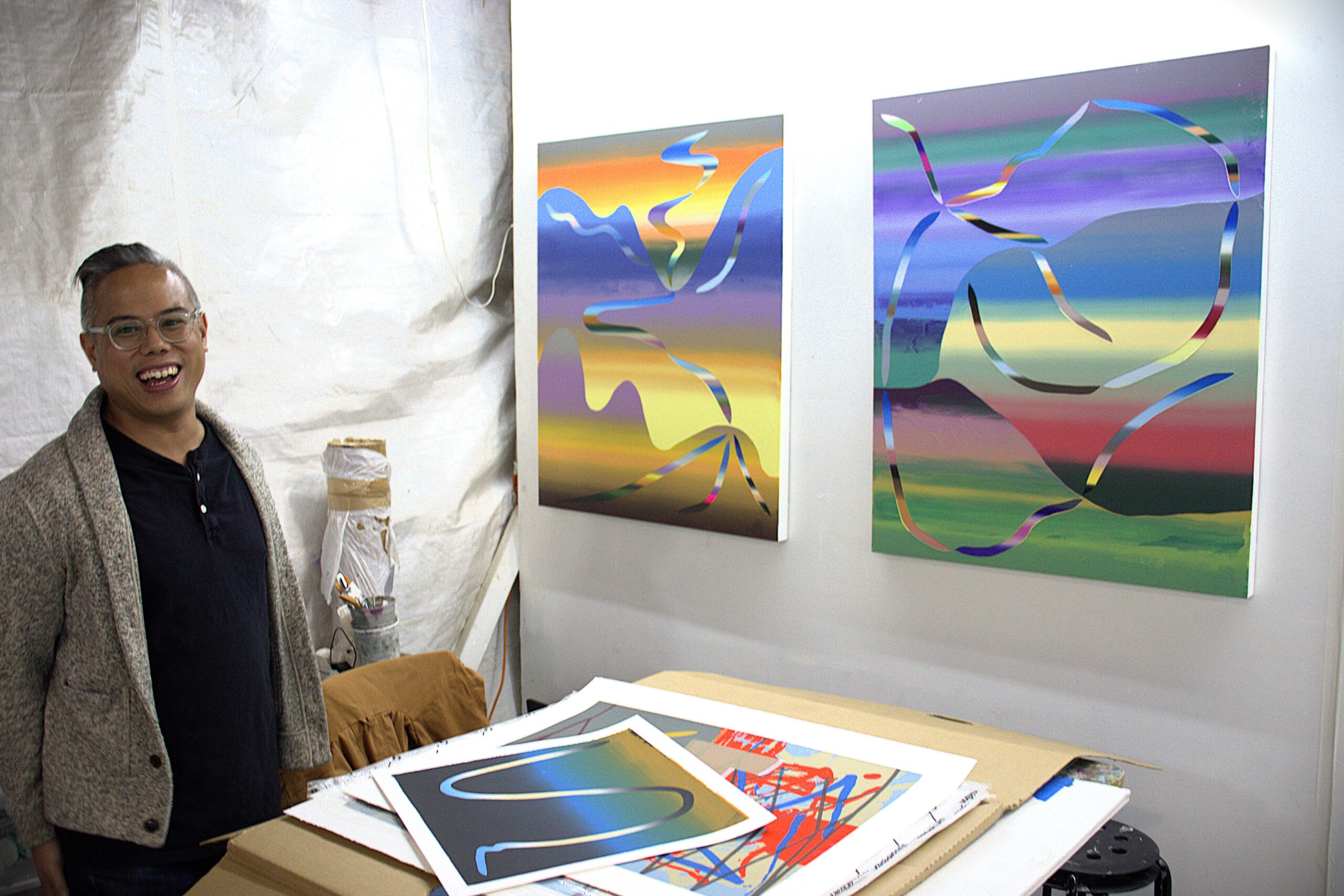 Roberto Jamora stands beside an open portfolio of prints in his studio.