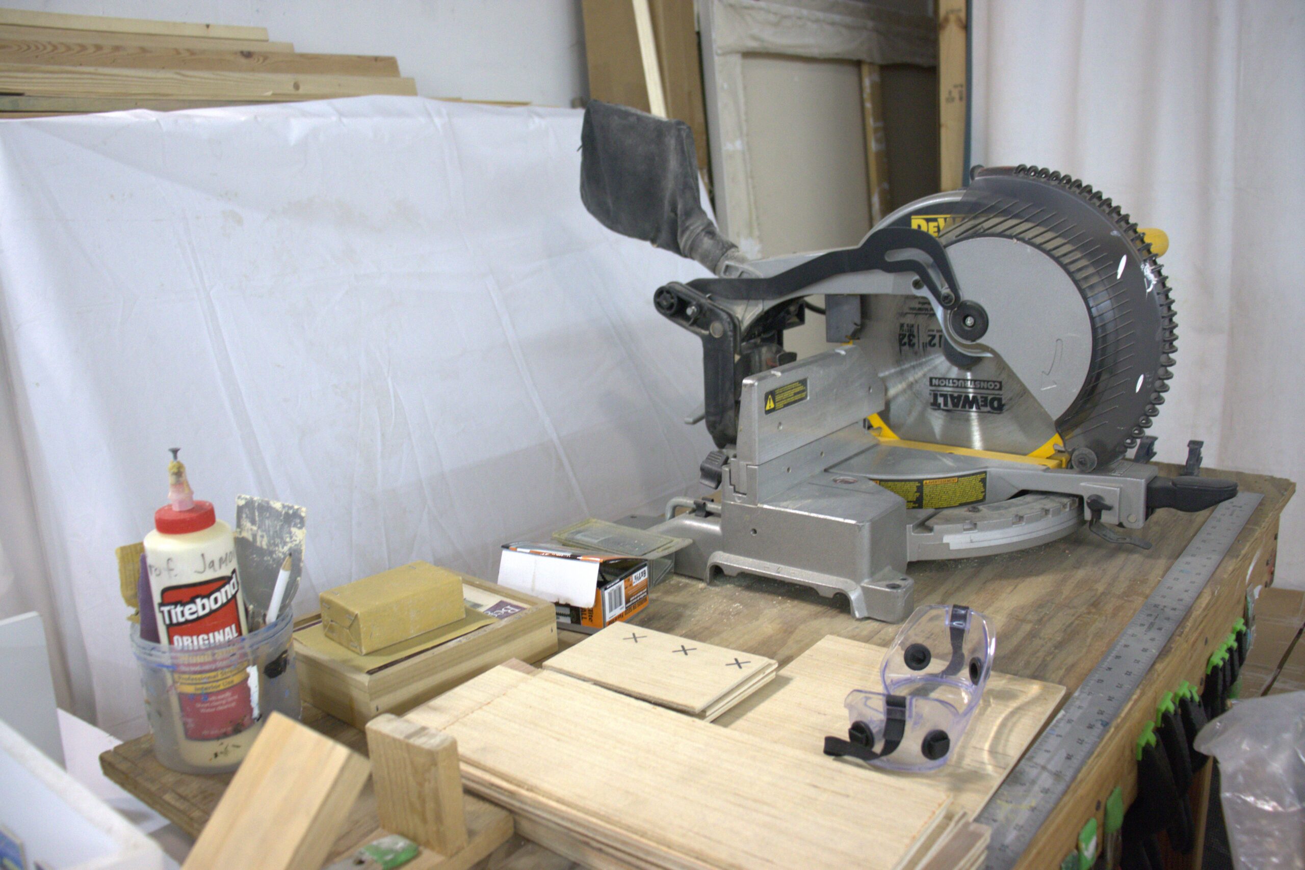 Roberto Jamora's woodworking tools in his studio, including a circular saw, goggles, and wood glue.