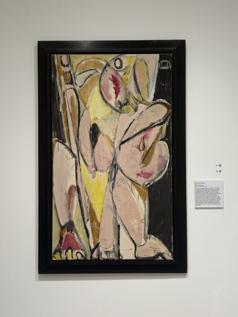 Abstract painting in creams, pinks, yellows, blacks, and browns, with thick black lines, next to placard with information on it.
