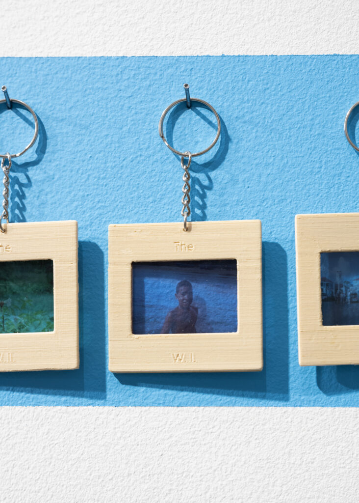 Close-up of row of keychains hanging on hooks against a blue background, with one fully in frame. The image is of a young boy, perhaps in front of water, with a blue tint.